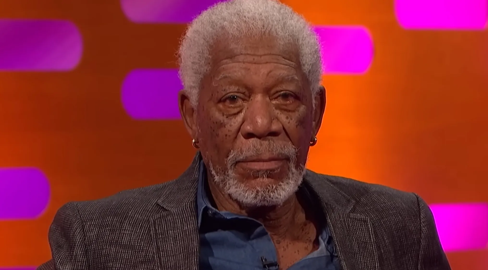 Close-up of the famous person, Morgan Freeman, a legendary actor with a distinctive voice, wearing gold earrings.