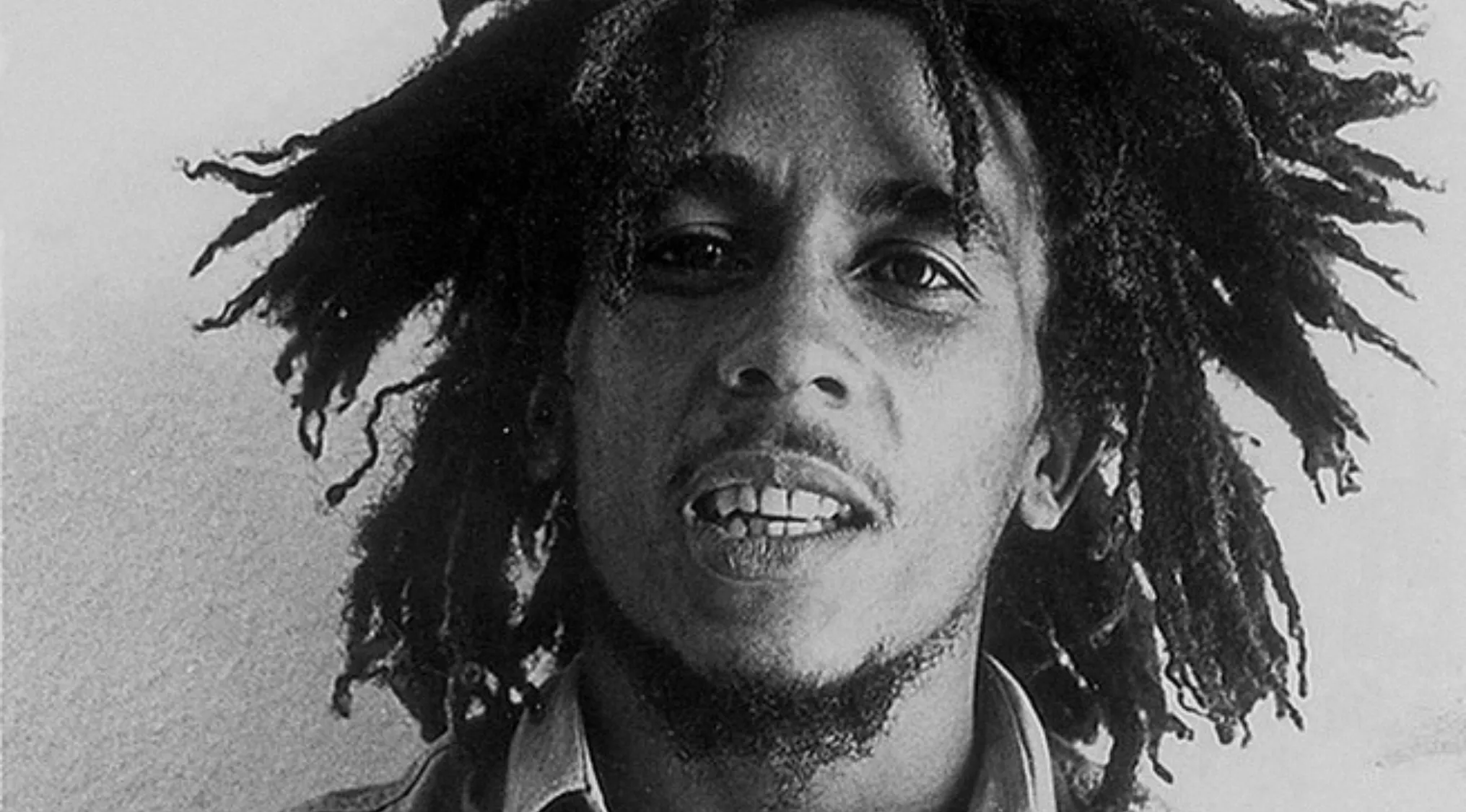 Black and white close-up of reggae music icon Bob Marley with long dreadlocks and a light beard.