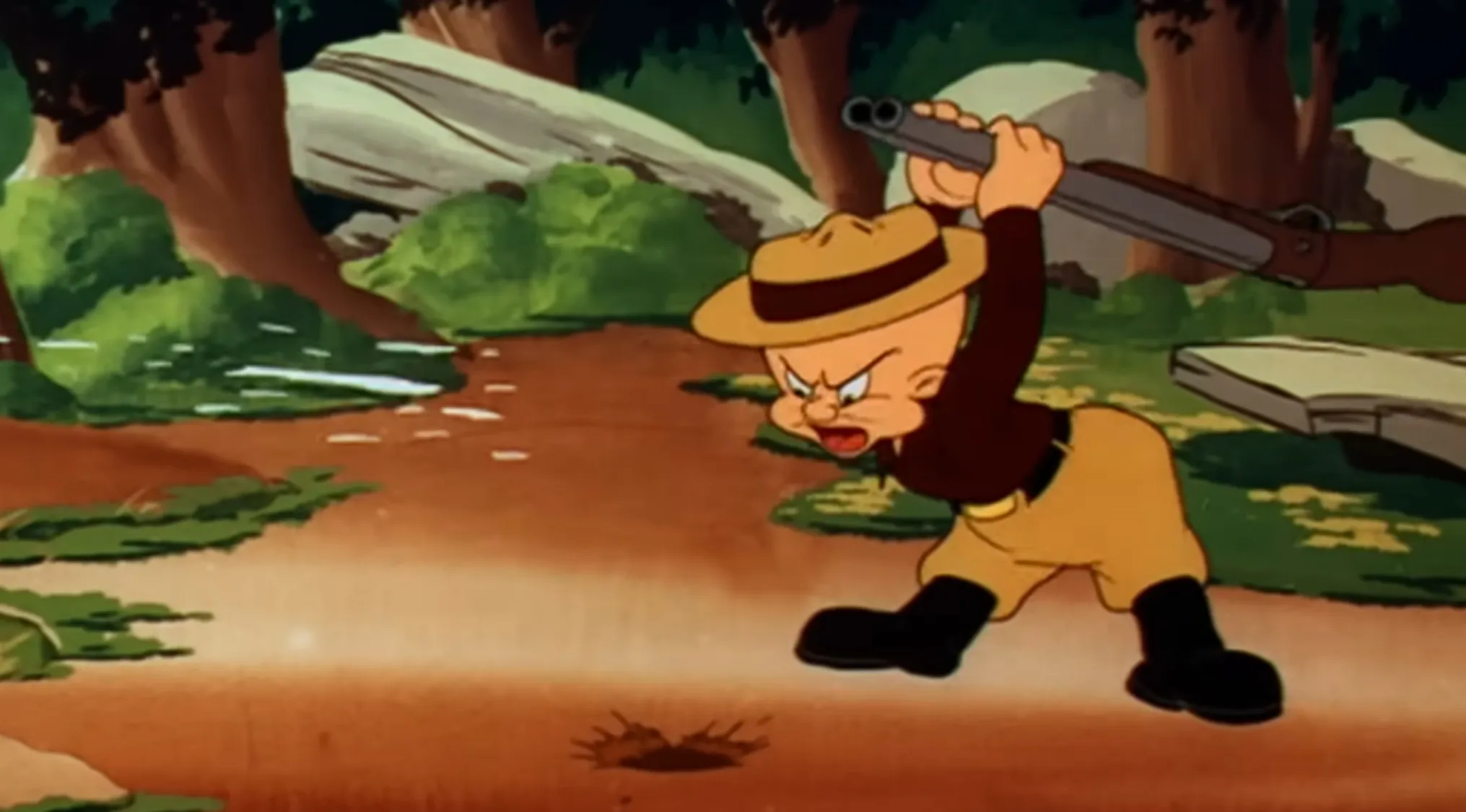 Saturday Morning Cartoons Trivia: Elmer Fudd, a hunter, angrily raises a shotgun over a small hole in the ground.