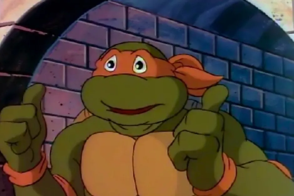 The Teenage Mutant Ninja Turtle Michelangelo, giving two thumbs up, smiling in a sewer setting.