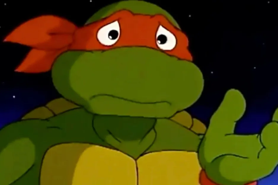 A sad Teenage Mutant Ninja Turtle, possibly Michelangelo, wearing an orange mask and reaching out a hand.
