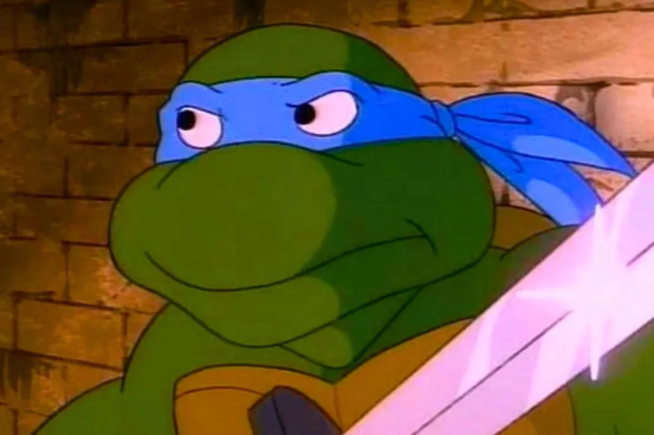 Leonardo, the Teenage Mutant Ninja Turtle, with a blue mask and sword, against a brick background. He's not Michelangelo.