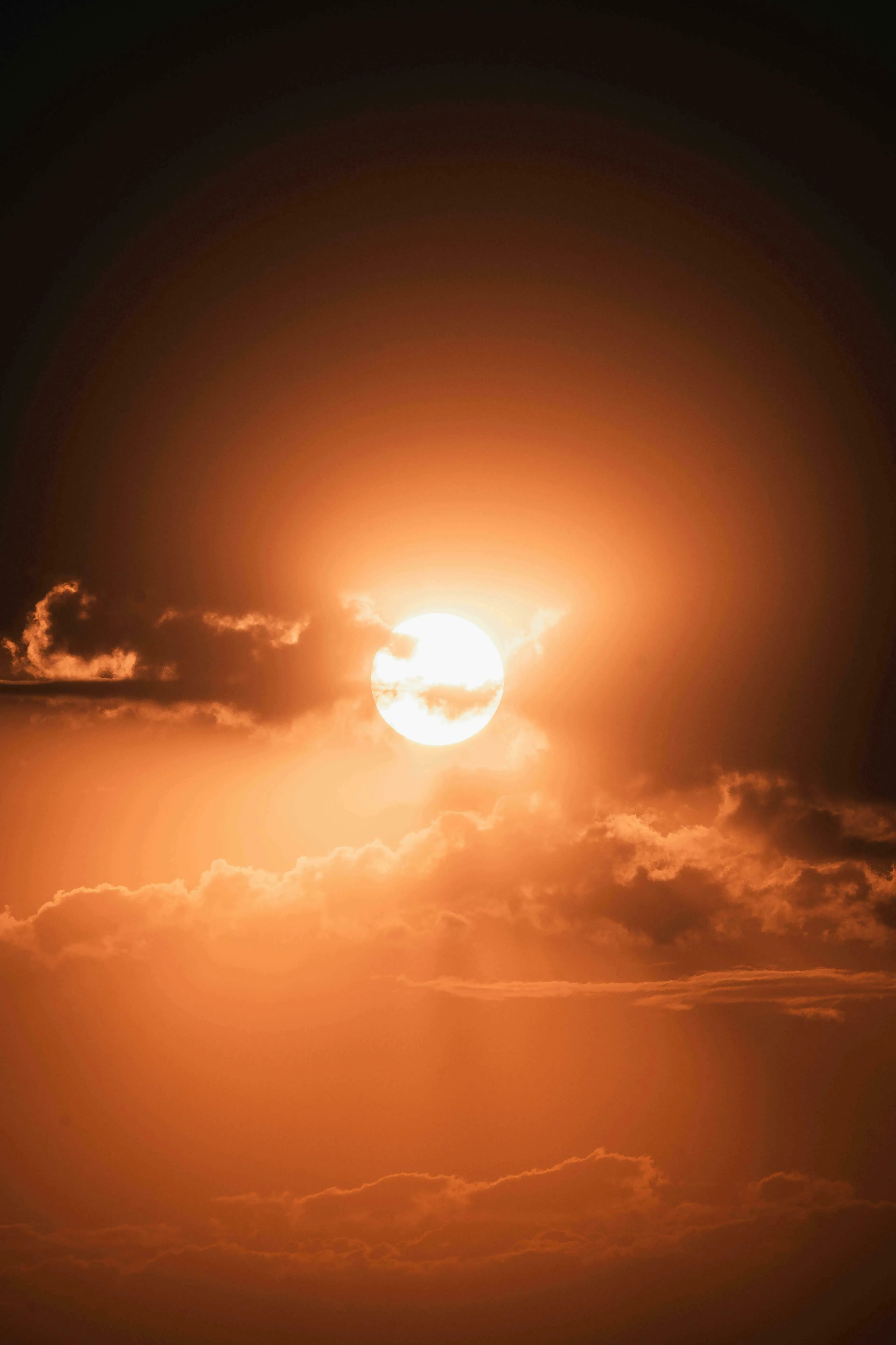 A glowing orange sun partially obscured by clouds, reminiscent of the immense energy in nuclear fusion.