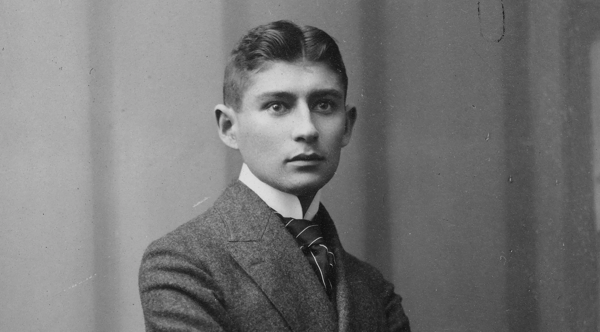 Franz Kafka, author of The Metamorphosis, in a black and white portrait, wearing a suit and tie.