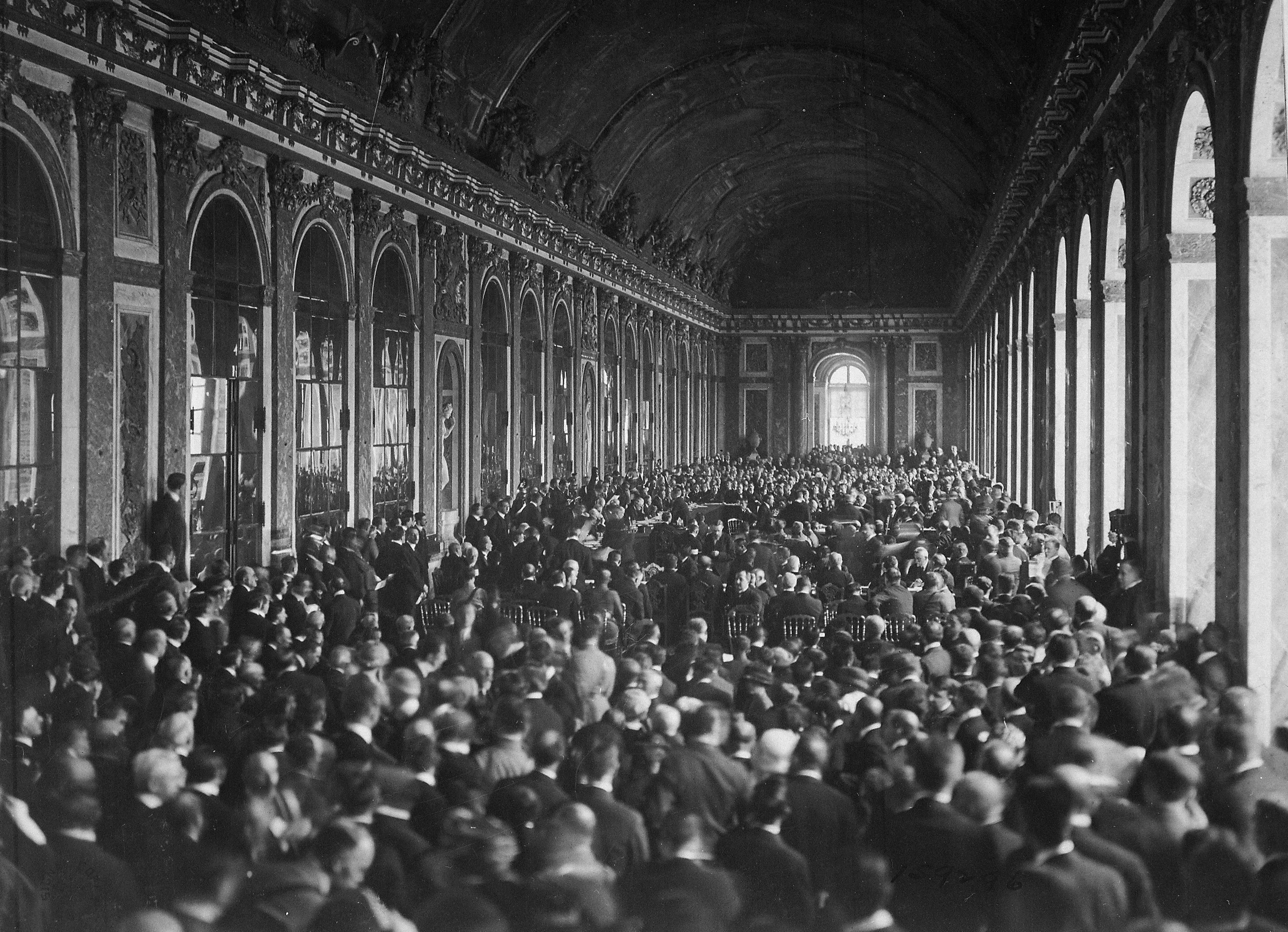 Large historic hall with many men seated, marking a key moment in the History of the Interwar Period between WWI and WWII.