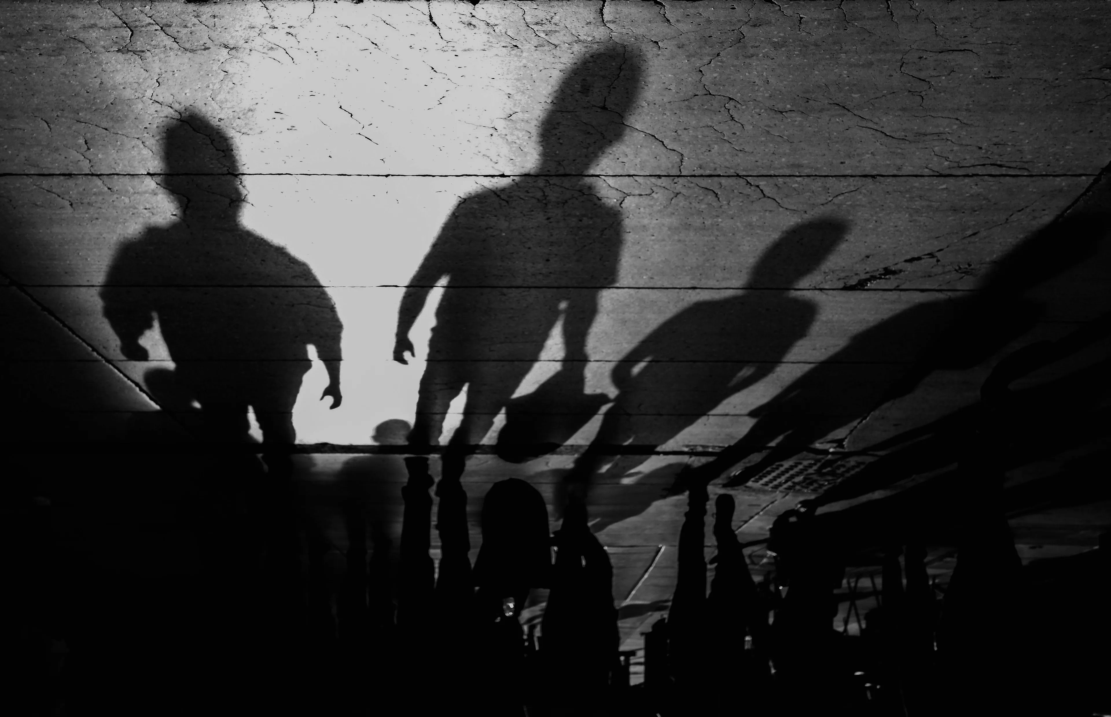 Black and white image depicting abstract human shadows cast on a cracked surface, illustrating the General Knowledge concept of mistaking illusions for reality.