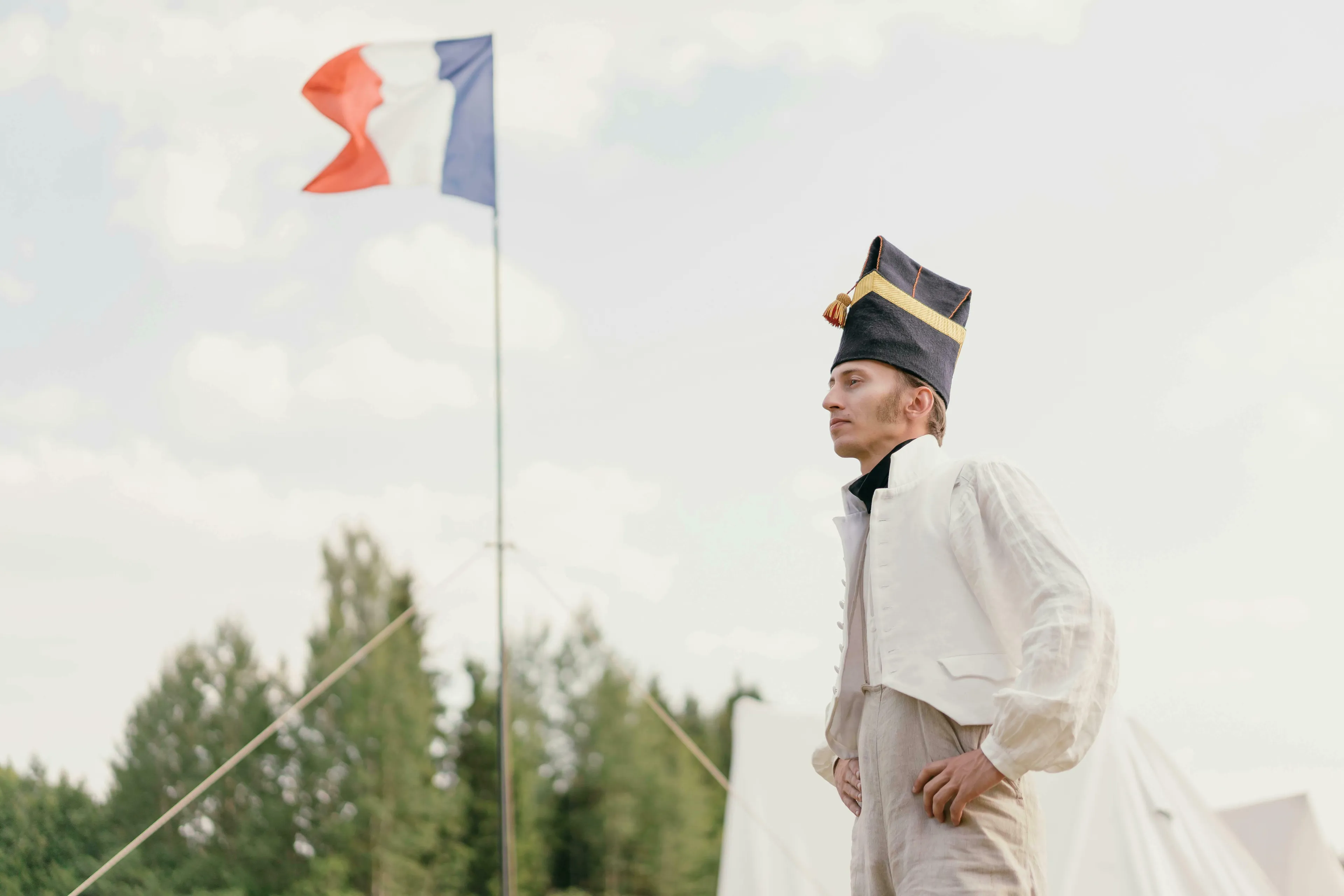 A person in 18th-century military attire, with a French flag waving in the background, representing the French Revolution.
