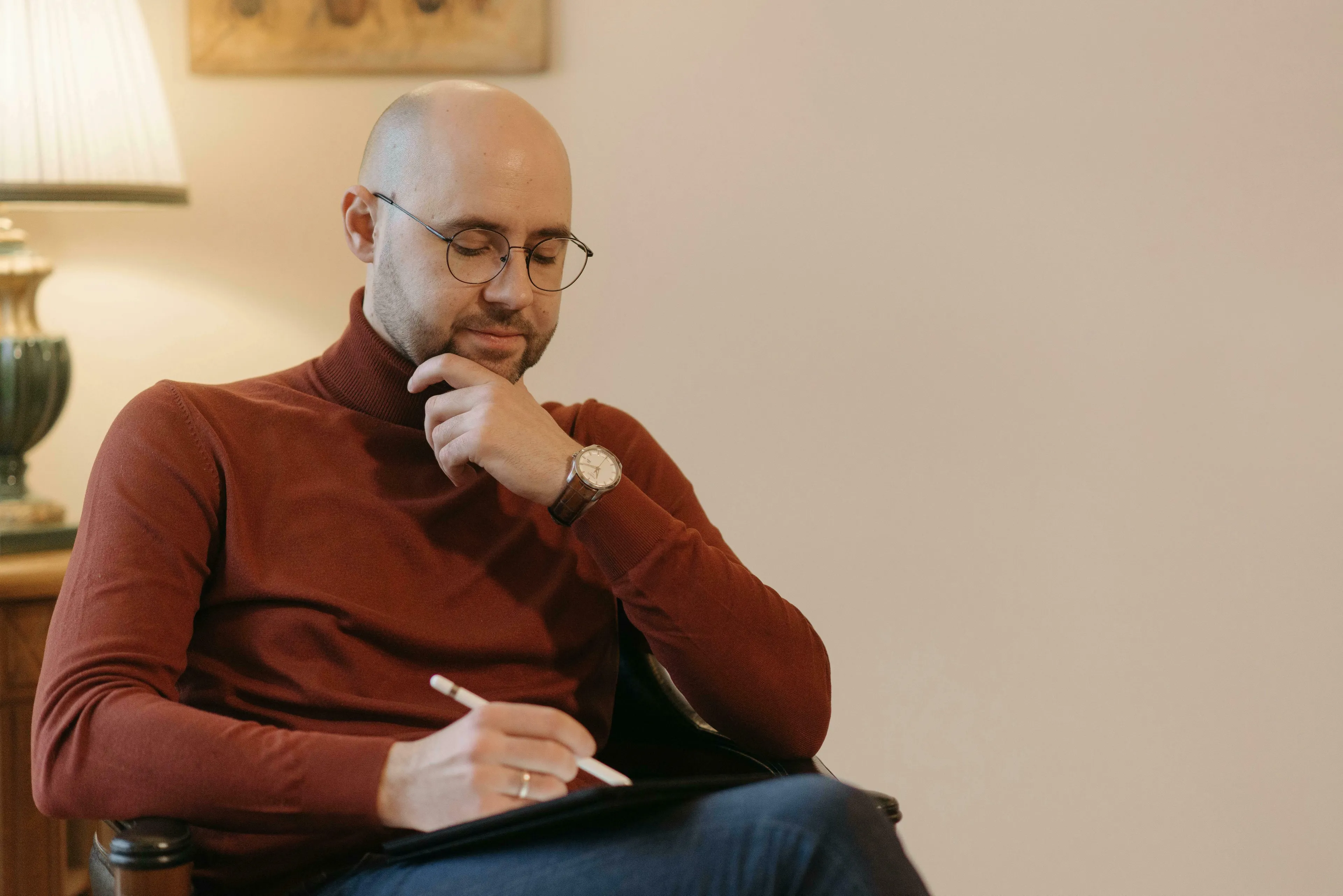 A man in glasses and a red turtleneck focuses on a tablet. He ponders general knowledge, a big ideas quiz.