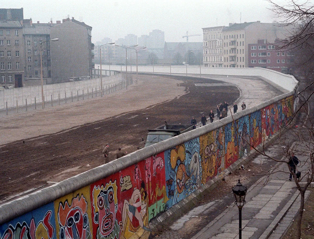 The Berlin Wall, adorned with colorful graffiti, separating East and West Berlin, highlighting a general knowledge quiz on historical divisions.