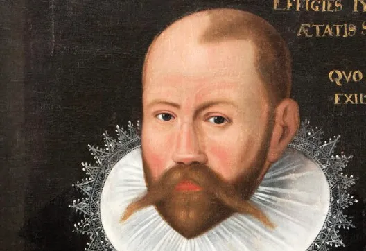 A historical portrait of Tycho Brahe, a bald man with a prominent reddish-brown beard and mustache, wearing a white ruffled collar.