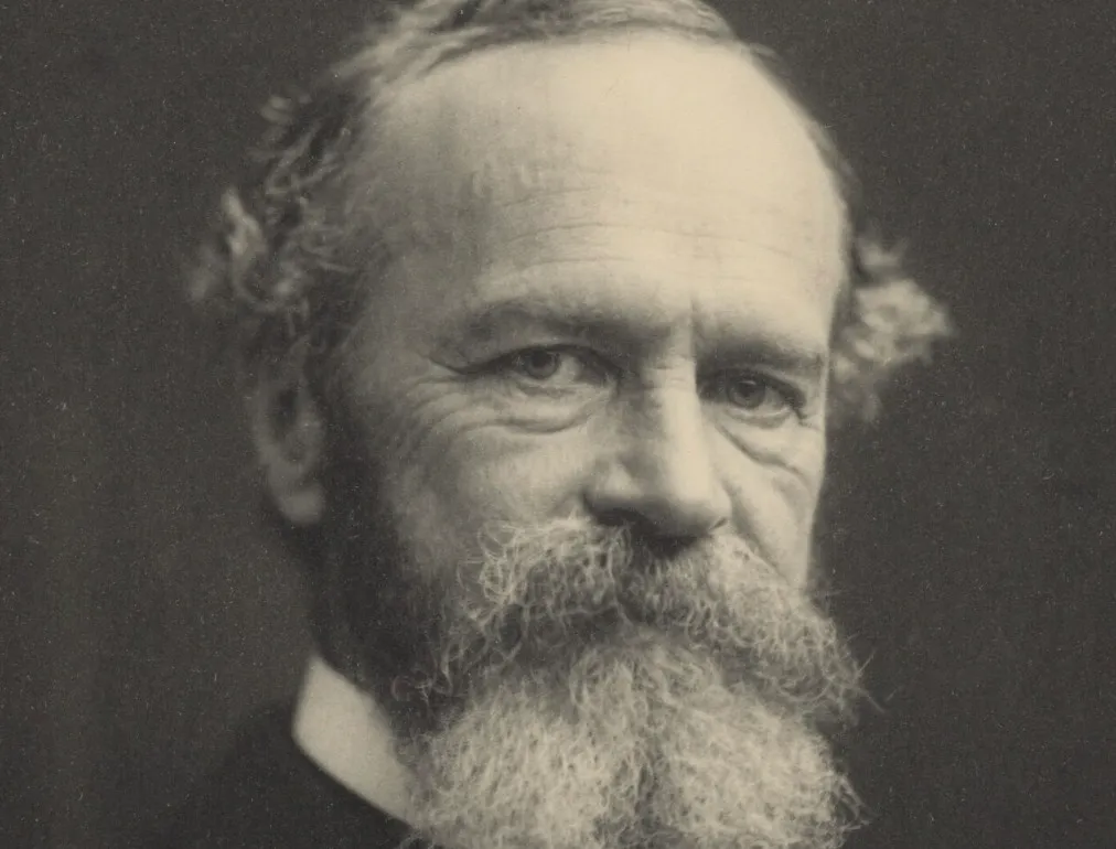 A black and white close-up of William James, a thinker with a full beard and thoughtful expression.