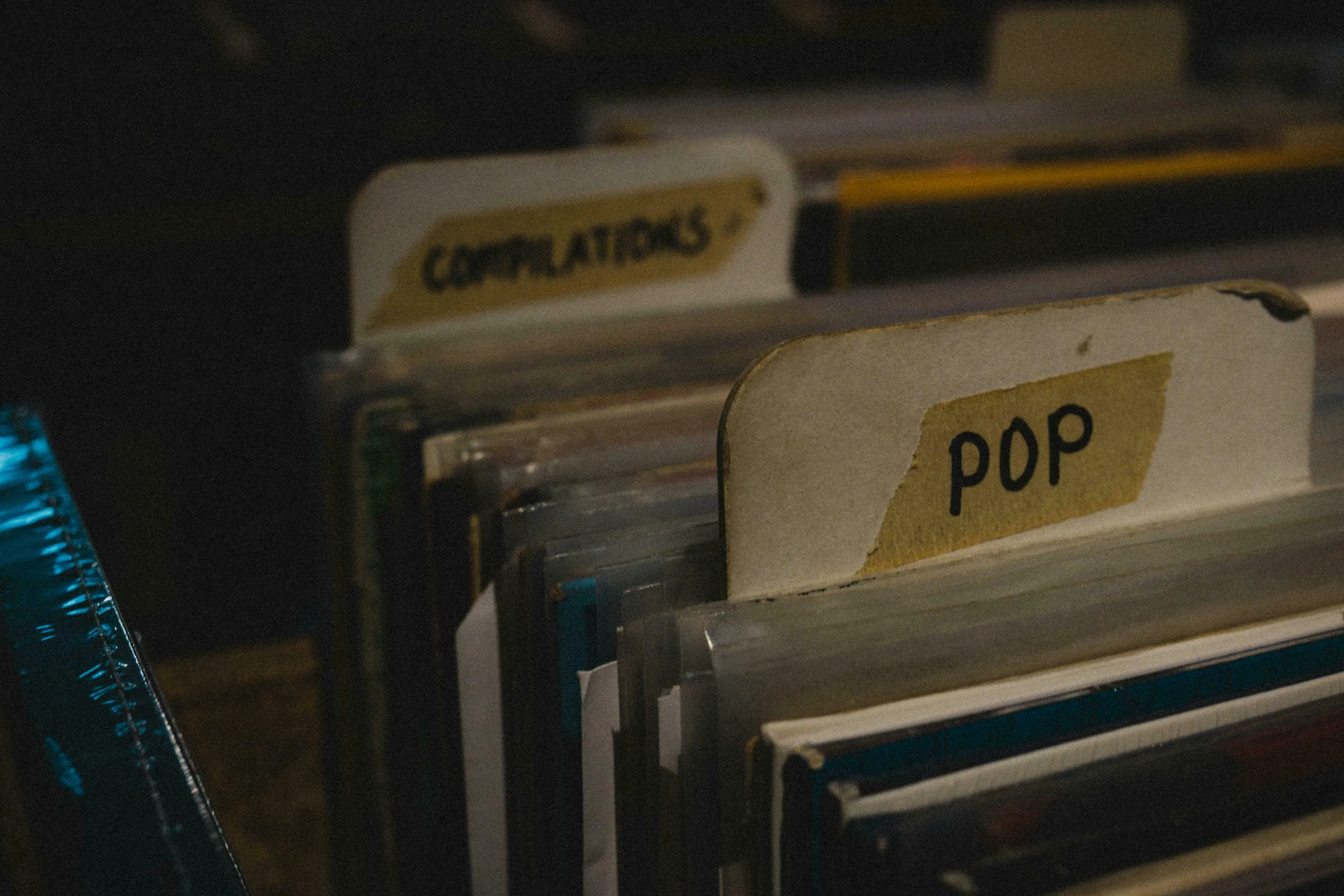Close-up of vinyl records in sleeves, with a labeled divider for POP music visible. General Knowledge music trivia.