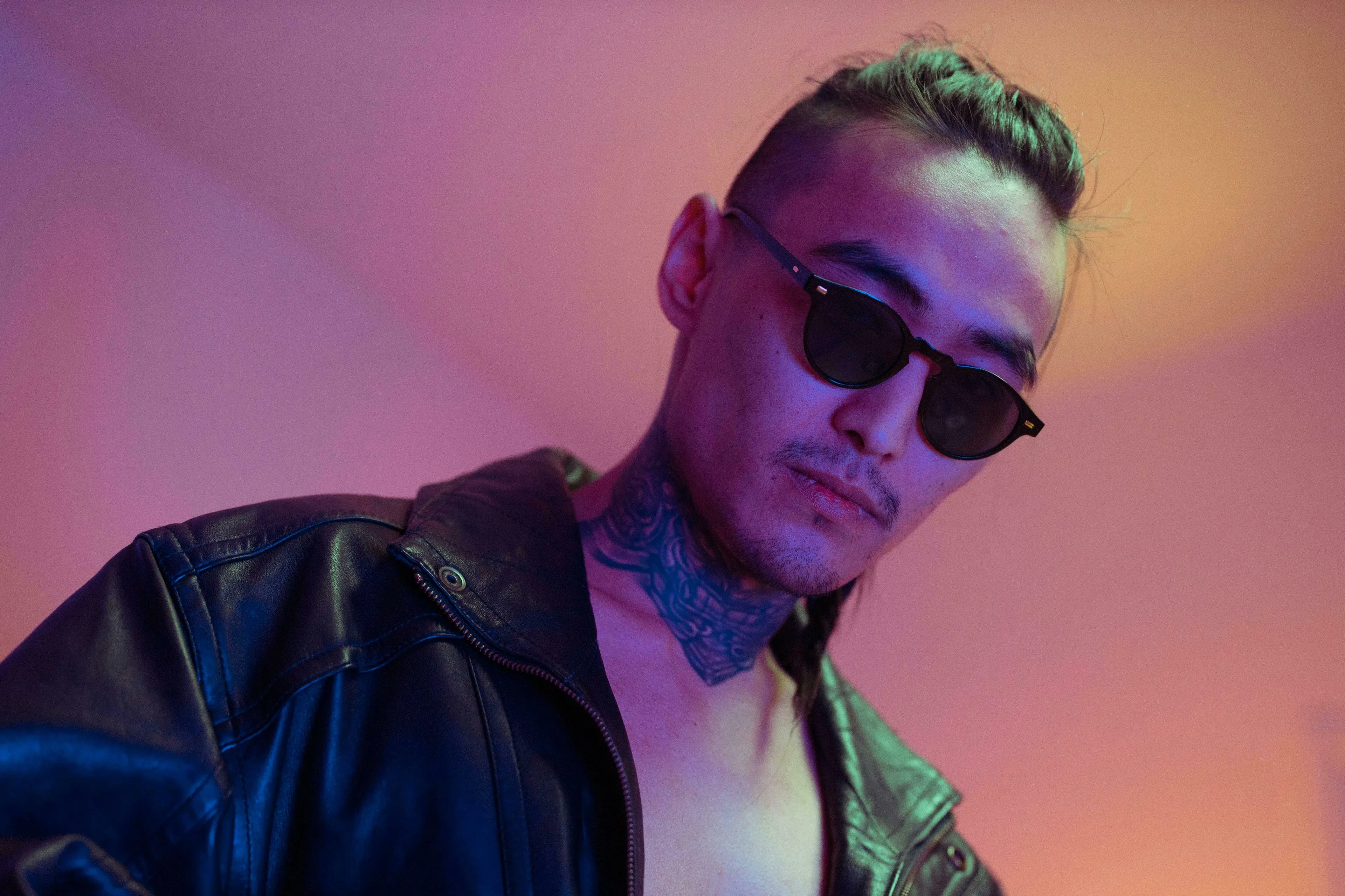 A man in sunglasses and a leather jacket, with a neck tattoo, under neon light. General Knowledge and Japan's organized crime.