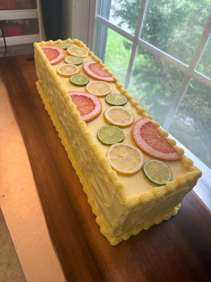 Rectangular citrus cake decorated with grapefruit, lemon, and lime slices on yellow frosting