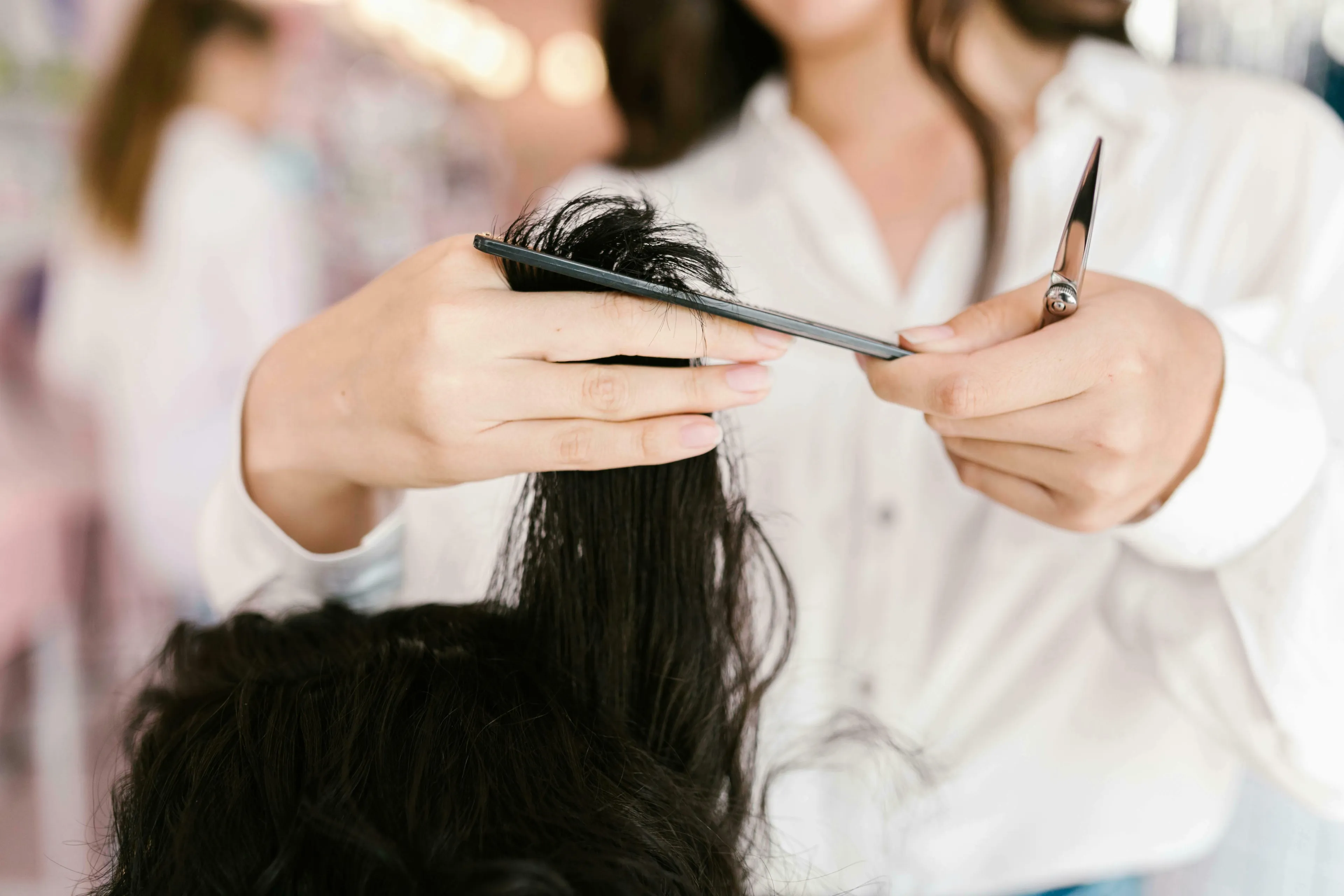 Hands holding hair, a comb, and scissors, ready to cut. How do you react to change when your hairdresser retires?