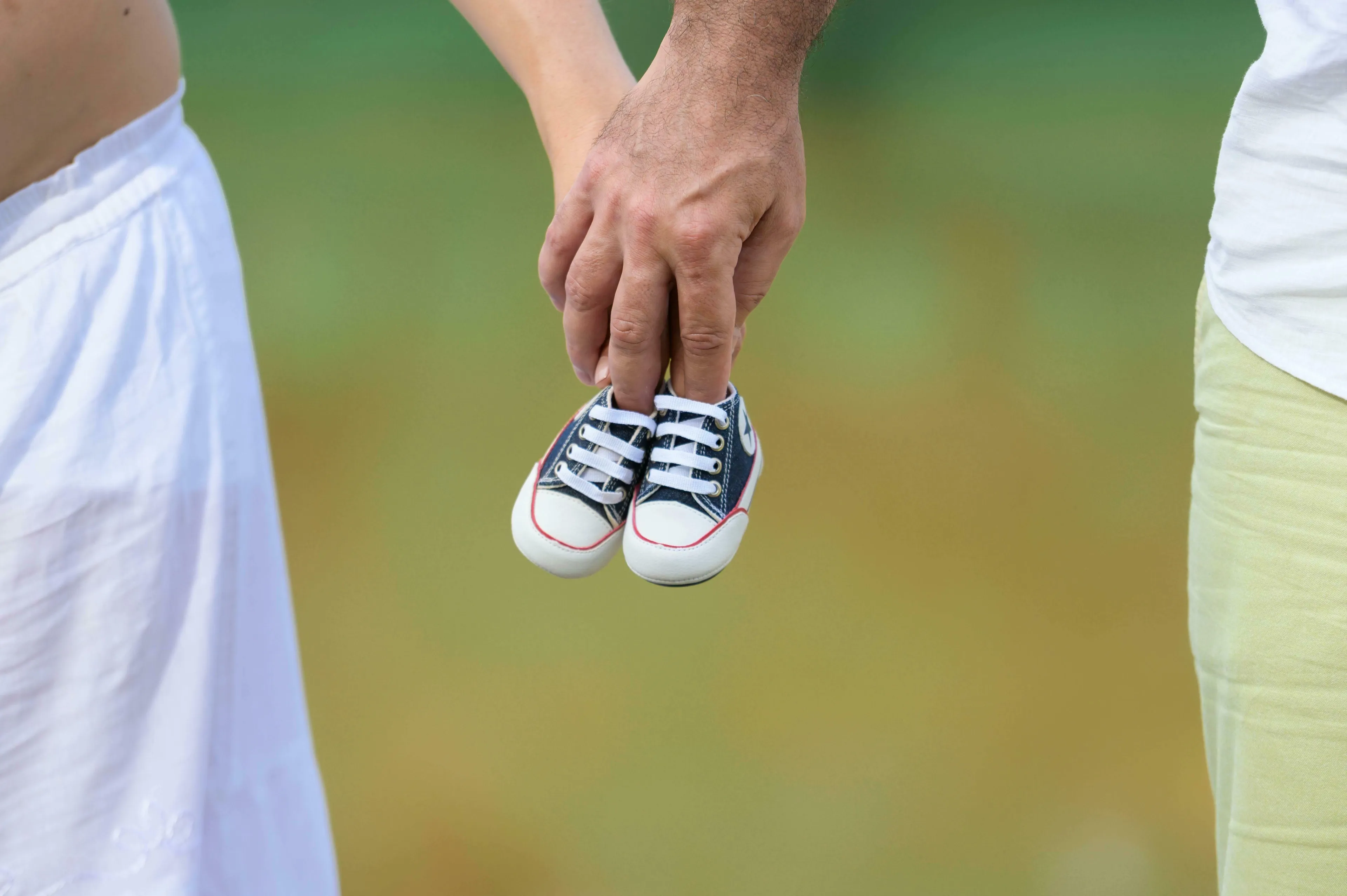 A couple holds tiny baby shoes, symbolizing exciting change and a friend expecting a baby.