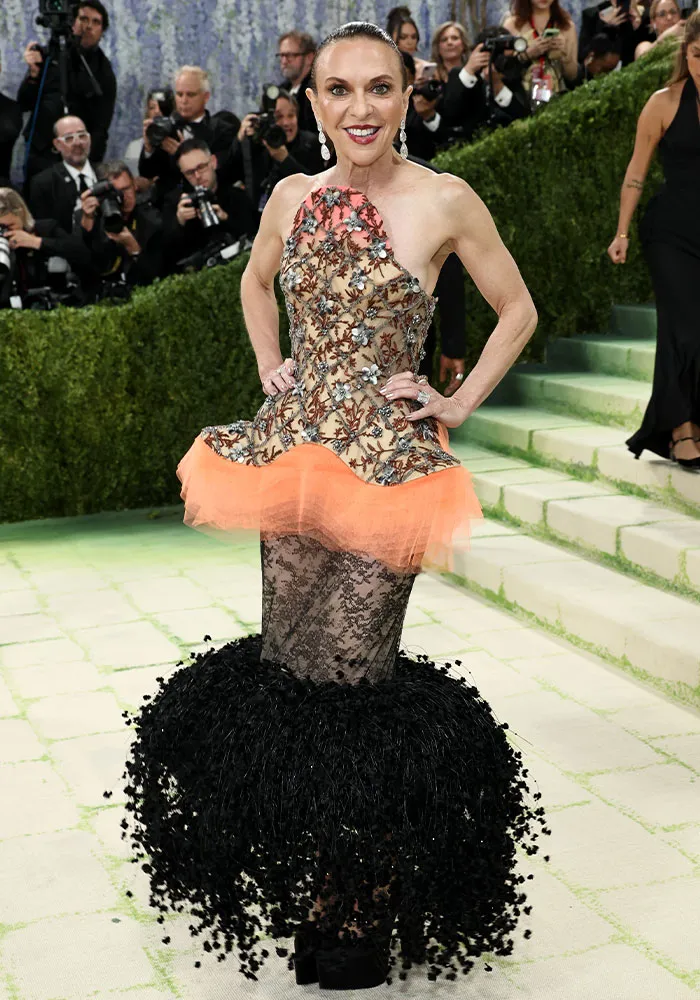 Woman in an elaborate, embellished dress with orange ruffles and a black feathered skirt, worst dressed at Met Gala.