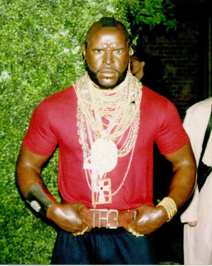 Wax figure of a muscular man wearing red shirt and gold chains in a celebrity wax figures exhibit