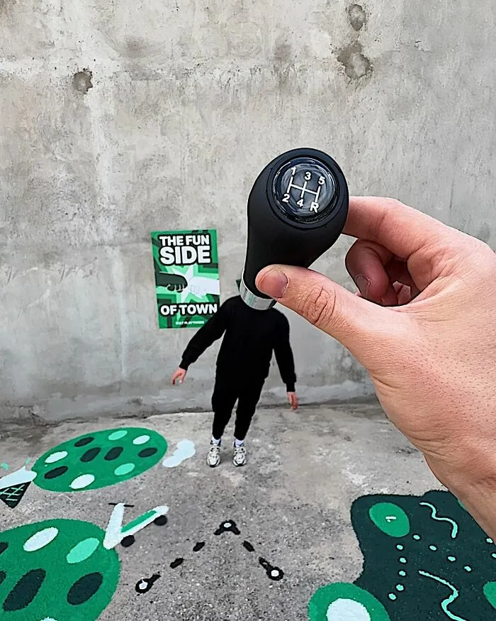 A hand holding a gear stick over a person's head, part of a clever photo manipulation making simple objects look like parts of cities.