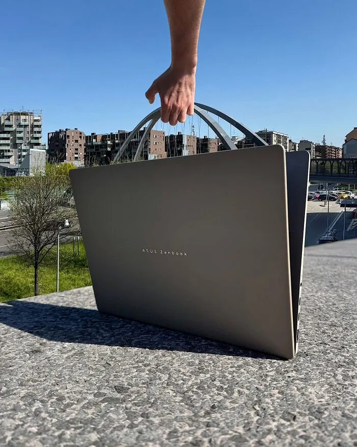 A hand holding a laptop like a briefcase, with a city skyline in the background, a clever photo manipulation.
