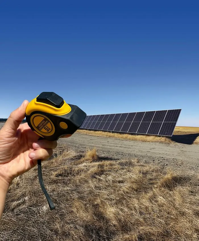 Ingenious photo manipulation features a tape measure extending into a solar panel array, turning a simple object into a part of a city.