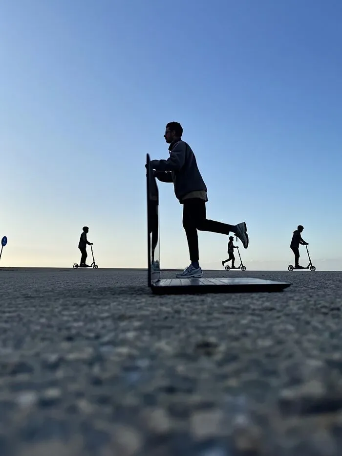 Clever photo manipulation of a person riding a scooter on a laptop screen, making simple objects look like parts of cities.