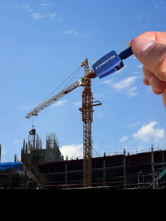 Clever photo manipulation of a hand holding a pencil sharpener over a construction site, making simple objects look like parts of cities.