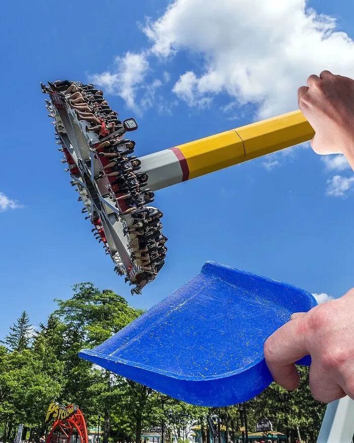 A photo manipulation of a hand holding a blue dustpan, making a city amusement park ride appear as if it's being held in the dustpan.