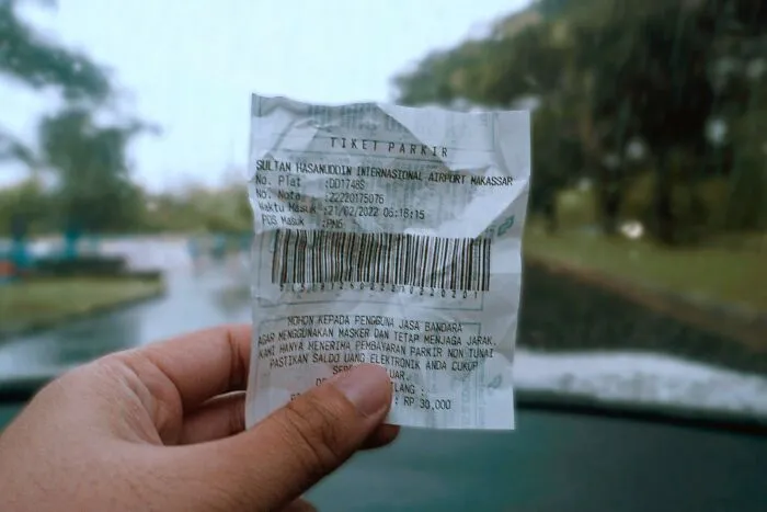 Hand holding crumpled parking ticket receipt in vehicle
