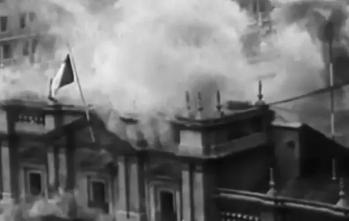 Historic black and white image of a building engulfed in smoke and destruction