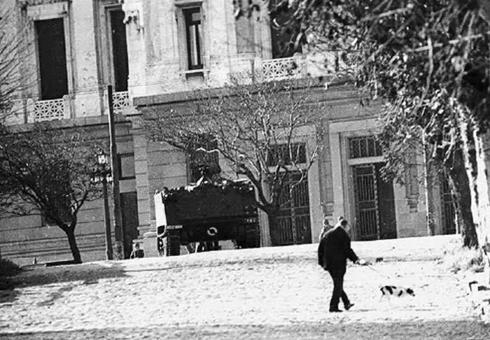 Black and white photo of man walking dog in stark historical city scene