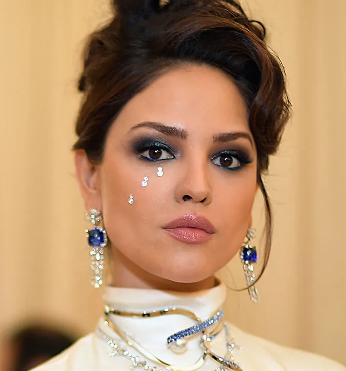 Woman with smoky eye makeup and jeweled decorations on face