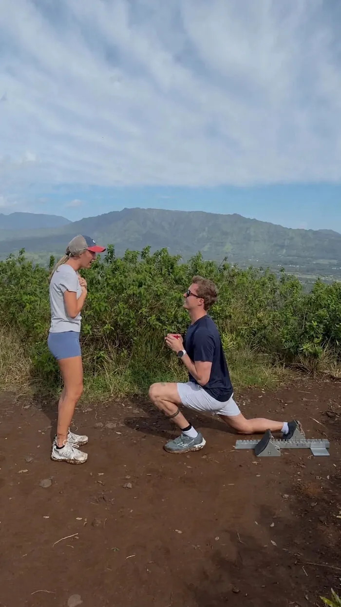 Man proposing to a woman on a mountain top. This viral proposal pic inspired hilarious edits.