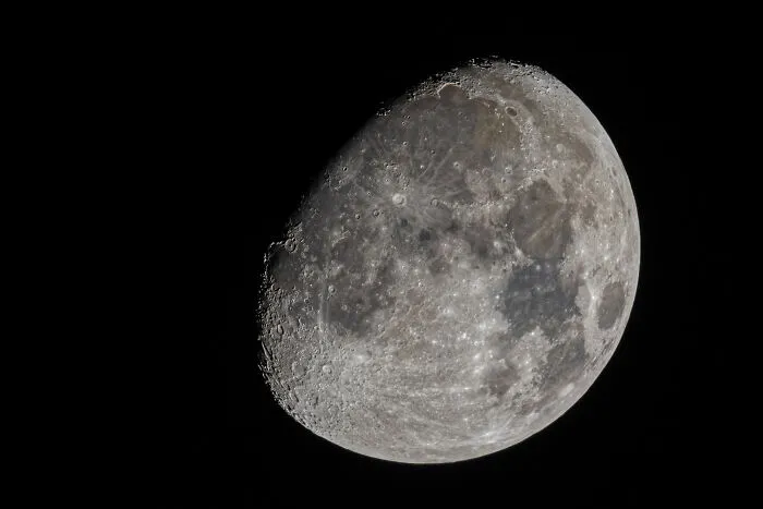 A detailed image of the moon's surface, showing craters and maria against a black sky. Wild encounters and intelligence.