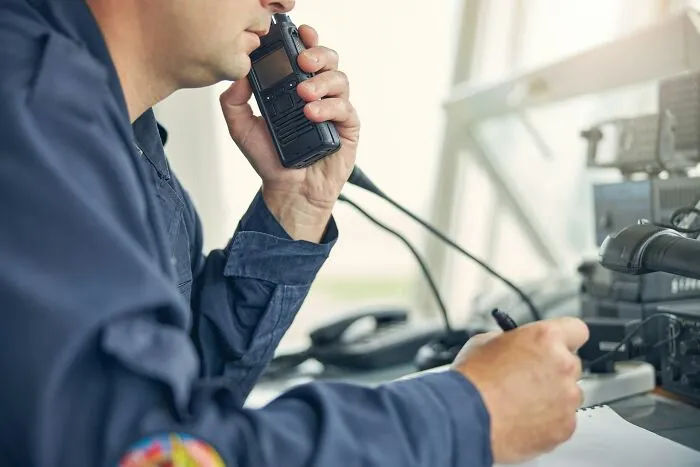 A person in a blue uniform speaks into a walkie-talkie, taking notes. Disturbing death stories often involve communication.