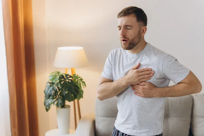 A man experiences chest pain, holding his hands to his chest. This image explores health expertise and professional facts.