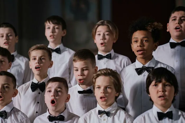 Young boys in white shirts and black bow ties singing in a choir, showcasing fun facts from their expertise.