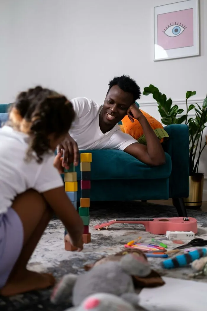 Father joyfully watching child play with blocks about parenting happiness