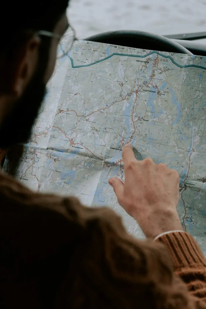 Person pointing at route on a folded map inside a car