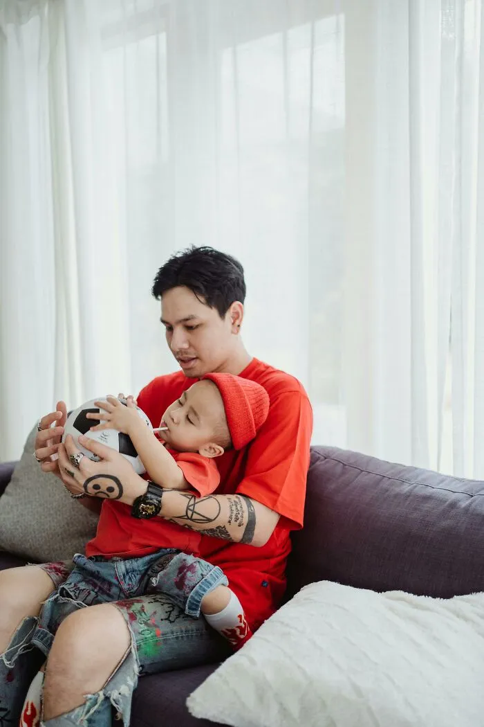 Father playing with toddler holding soccer ball, bonding with kids