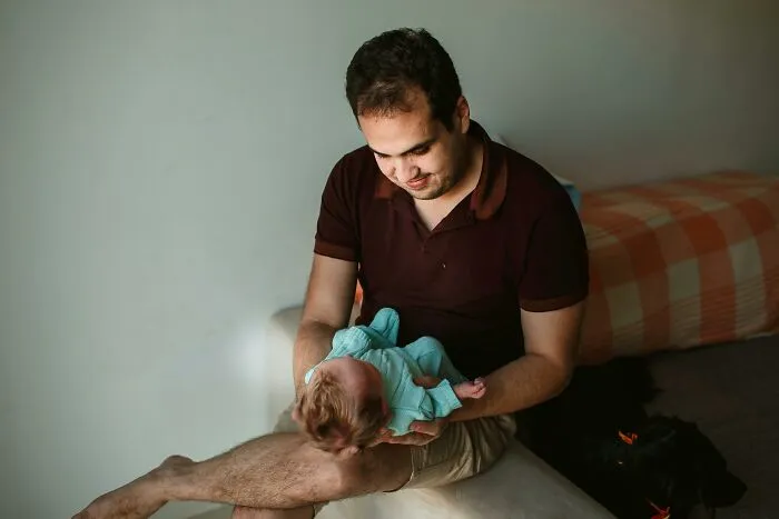 Man holding newborn baby in his arms at home showing fatherhood experience