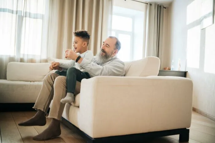 Happy father with son playing on couch, showing kids happy experience
