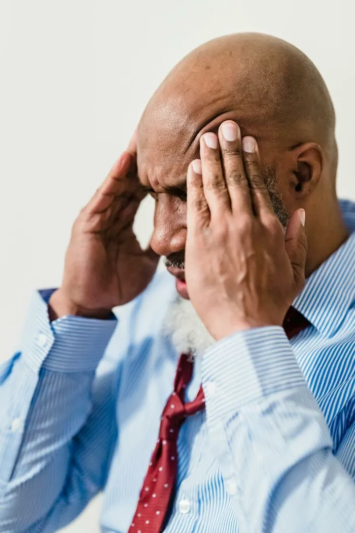 A man with hands on his temples, showing stress from wedding drama stories.