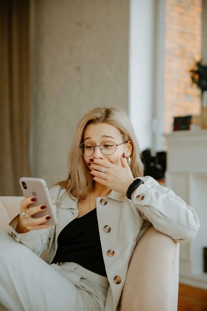 Surprised woman with glasses reacting to phone message