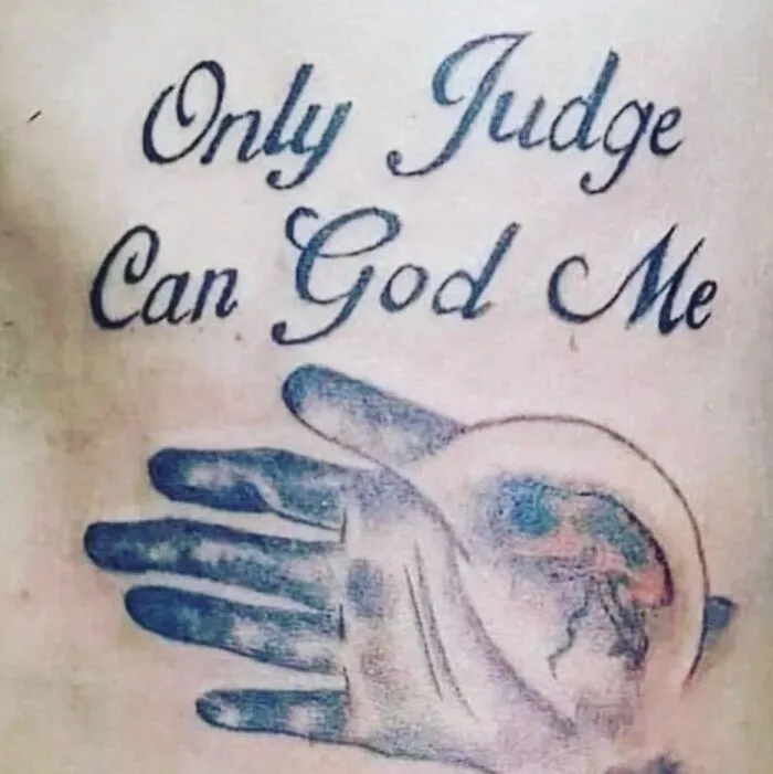 A tattoo fail with the text Only Judge Can God Me and a hand holding a globe.