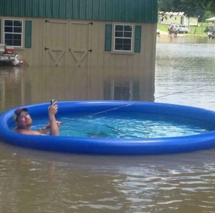 Man fishing in a small pool floating on floodwater