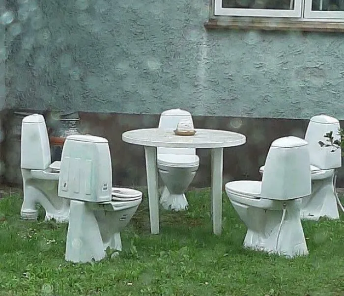 Outdoor table and chairs made from white toilets in a grassy yard