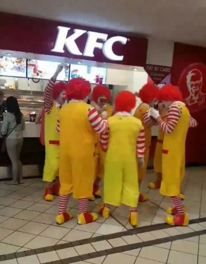Group of people dressed as Ronald McDonald clowns inside a KFC restaurant
