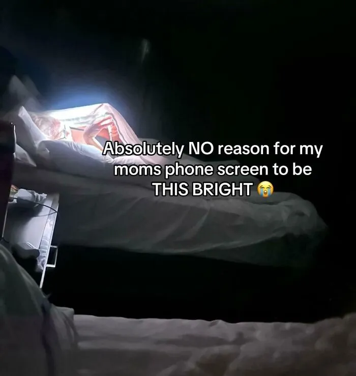 Bright phone screen shining in dark room with funny caption