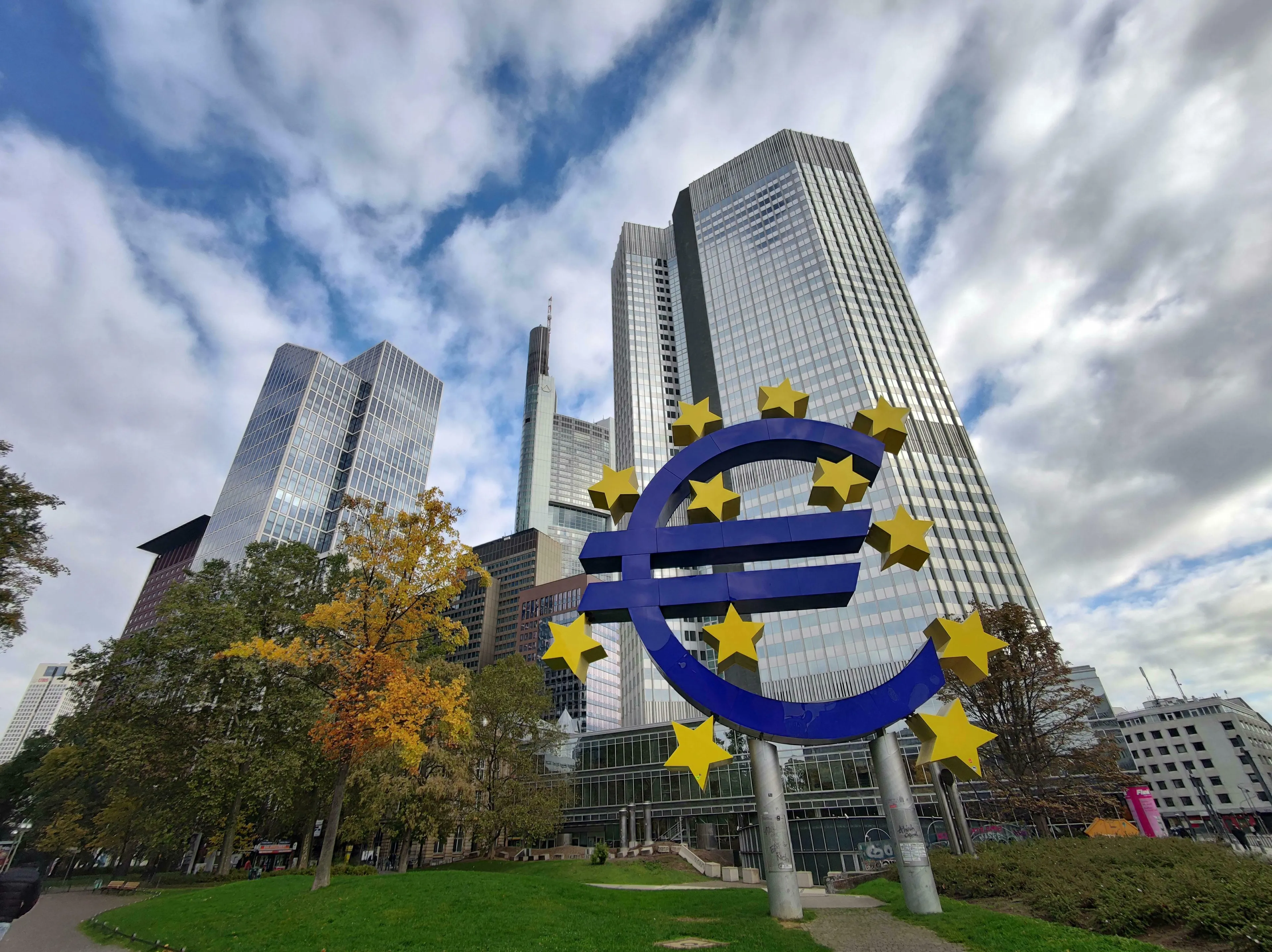 A large blue Euro symbol with yellow stars stands before modern skyscrapers. General knowledge quiz: Europe questions, European Central Bank.